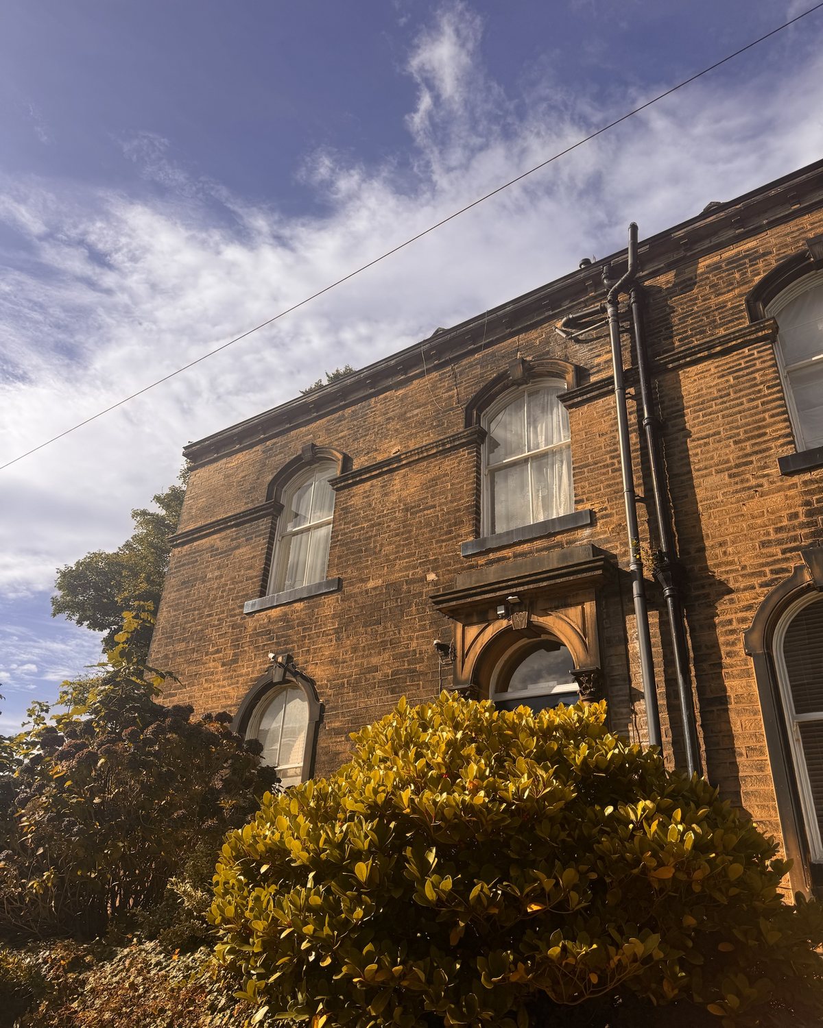 A stone house with arched sash windows under a blue sky.