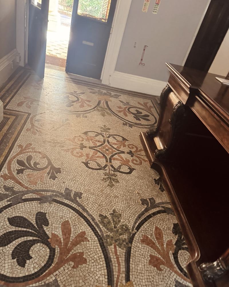 A mosaic hall floor with scrolling floral patterns.