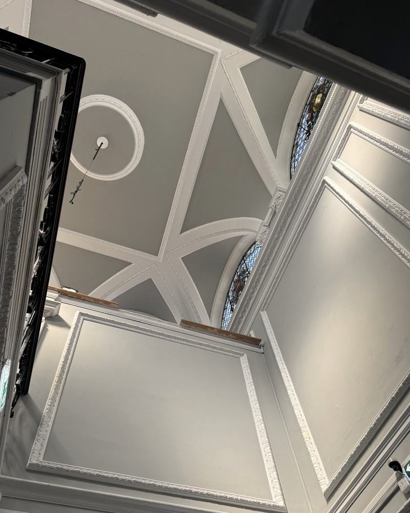 Looking up a panelled, vaulted stairwell.